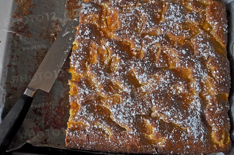 Baked fig cake on baking tray with baking paper and knife