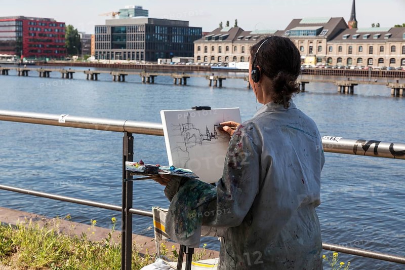 Painter with easel sketches the Oberbaum Bridge in Treptow