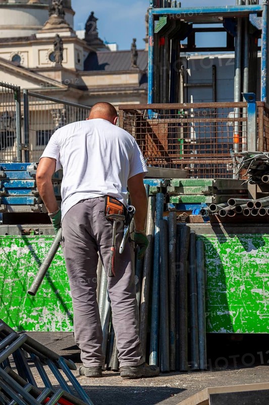 Construction worker loading a truck with scaffolding poles