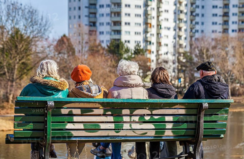 Senior citizens with a carer sitting on a wooden bench at the Segeluchbecken in the Maerkisches Viertel