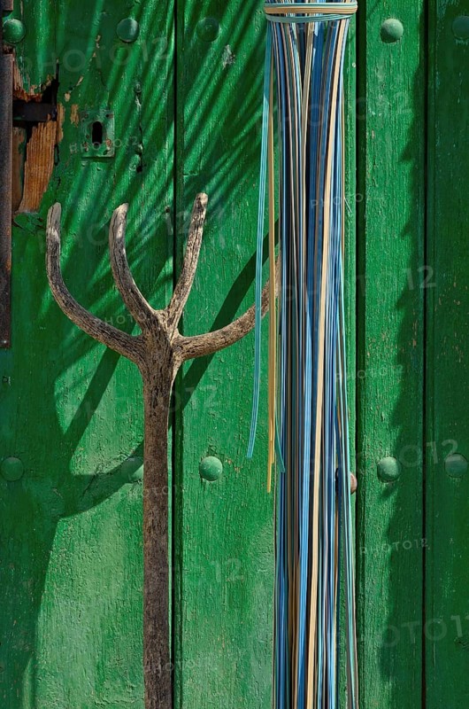 Wooden pitchfork leaning against green wooden door
