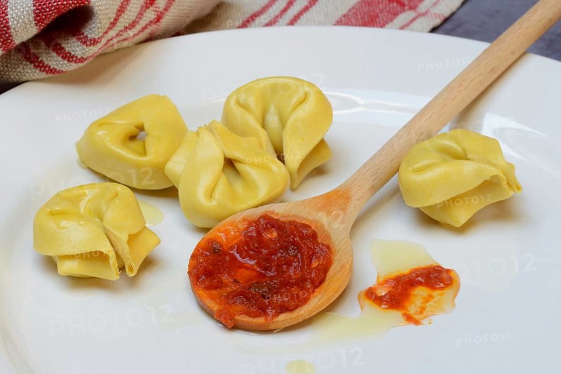 Pasta and cooking spoon with tomato sauce on plate