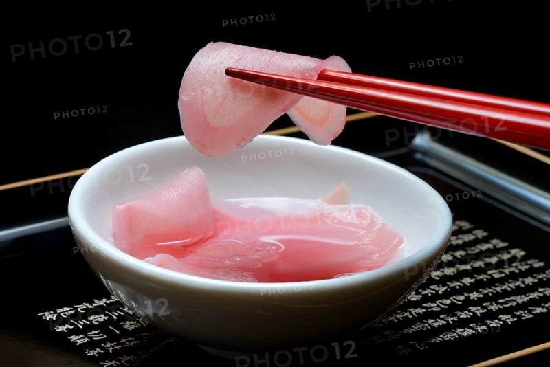 Sliced pickled ginger on chopsticks and in bowl