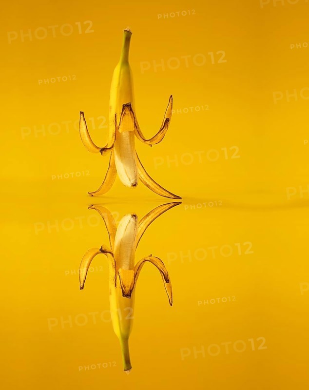 Banana with peel against a yellow background
