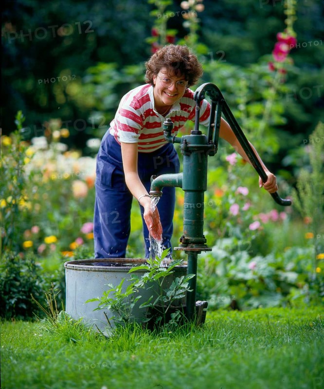 Woman pumps water in the garden