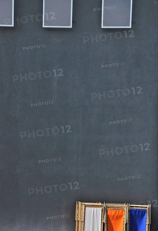 Grey wall with reflectors and coloured deck chairs in park
