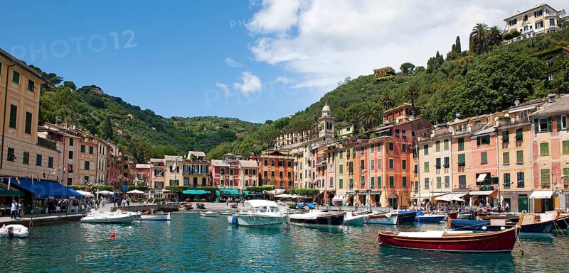 Panoramic photo of harbour of former fishing village Portofino with small boats in sheltered bay and pastel coloured houses