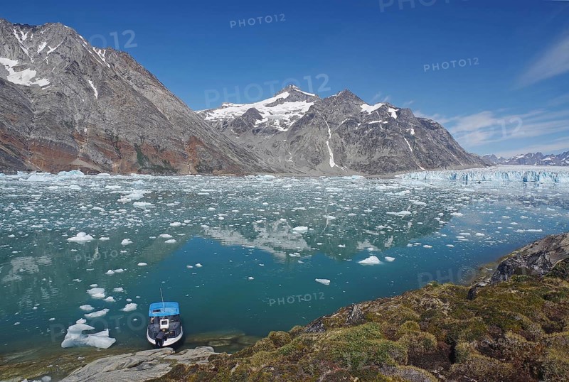 Small boat in a fjord with ice and icebergs