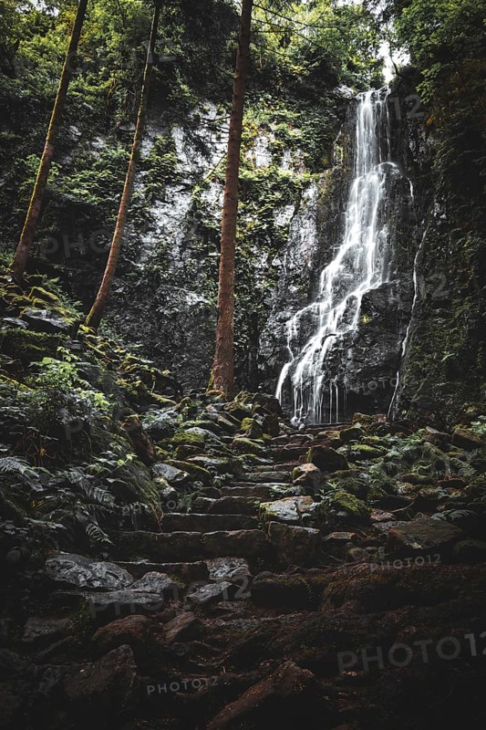The Burgbach waterfall in the middle of the green forest. Waterfall in Schapbach
