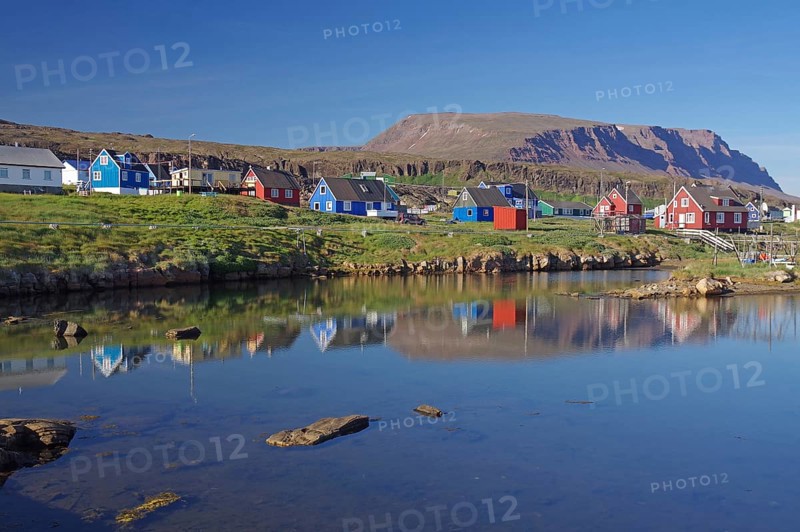 Wooden houses reflected in a body of water on a calm summer evening