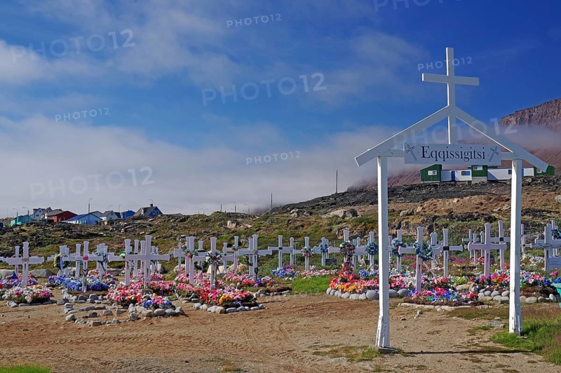 Wooden crosses in front of graves decorated with colourful artificial flowers