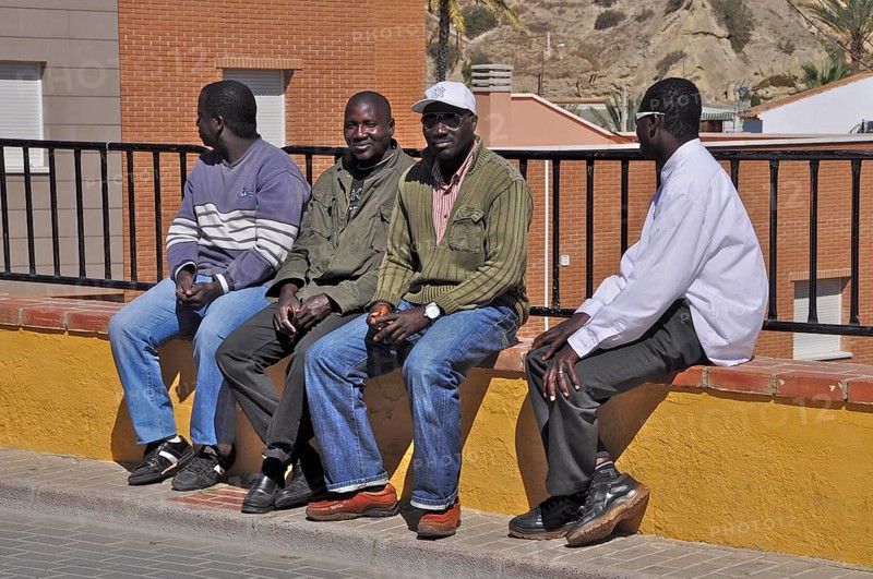 African men sitting on the wall of a garden fence
