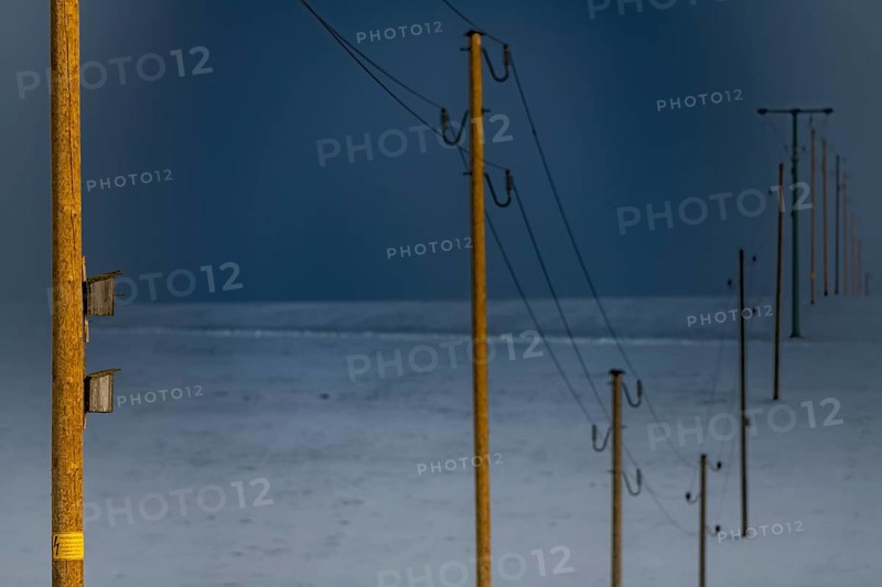 Electricity pylons in winter landscape against dramatic sky