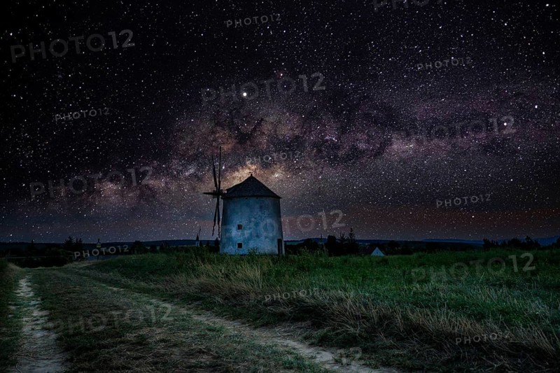 The Old Windmill of Tes iin the night with Milky Way and starry sky. Windmill made of stone and wooden wings in Tez