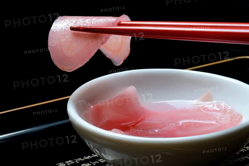 Sliced pickled ginger on chopsticks and in bowl
