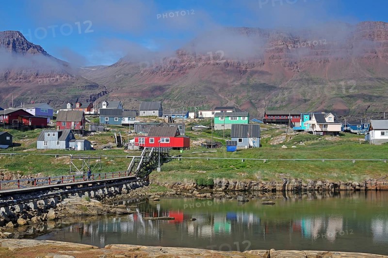 Simple bridge leading to houses reflected in a body of water