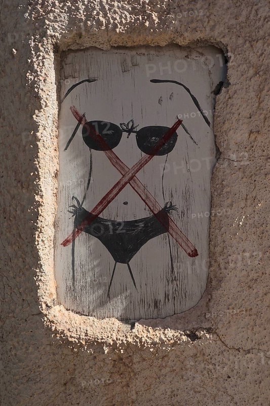Wooden sign with bikini forbidden on wall of restaurant