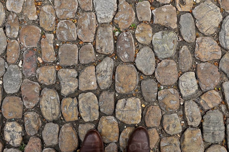 Brown shoe tips on brown stone pavement