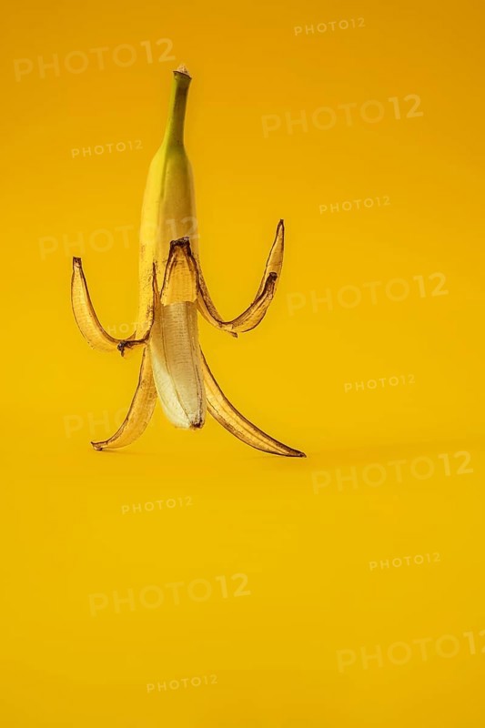 Banana with peel against a yellow background