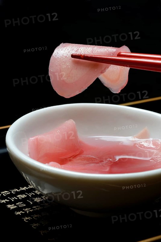 Sliced pickled ginger on chopsticks and in bowl