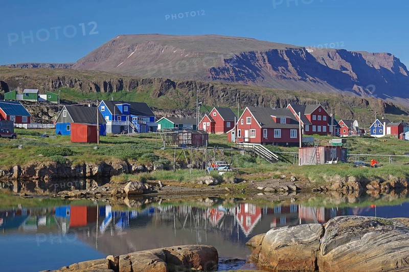 Wooden houses reflected in a body of water on a calm summer evening