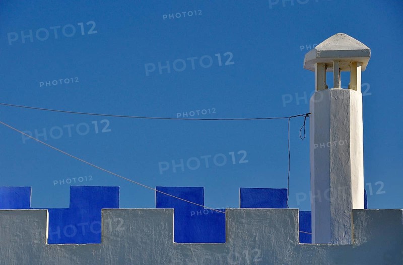 Chimney with white and blue battlements against the blue sky