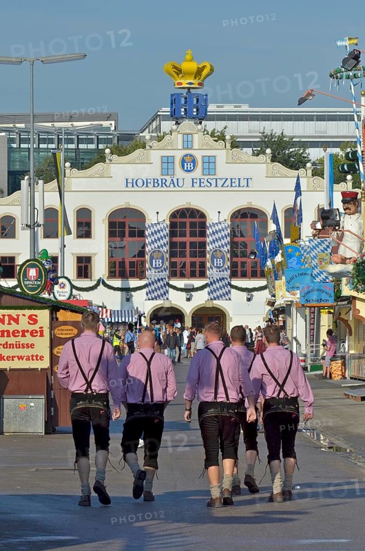 Group of men in traditional traditional costume with lederhosen in front of Hofbraeu tent