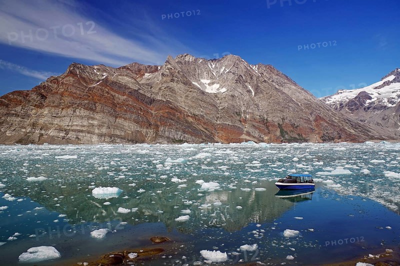 Small boat in a fjord with ice and icebergs