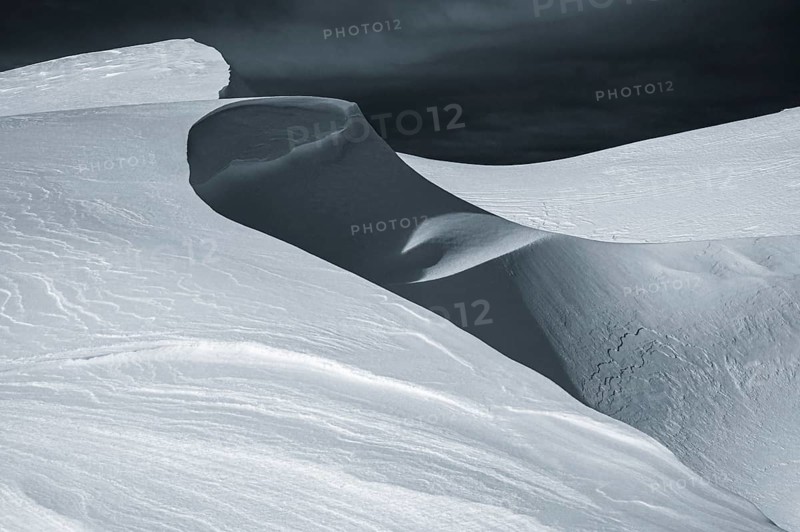 Snow cornice against a dark sky at the summit of Toreck