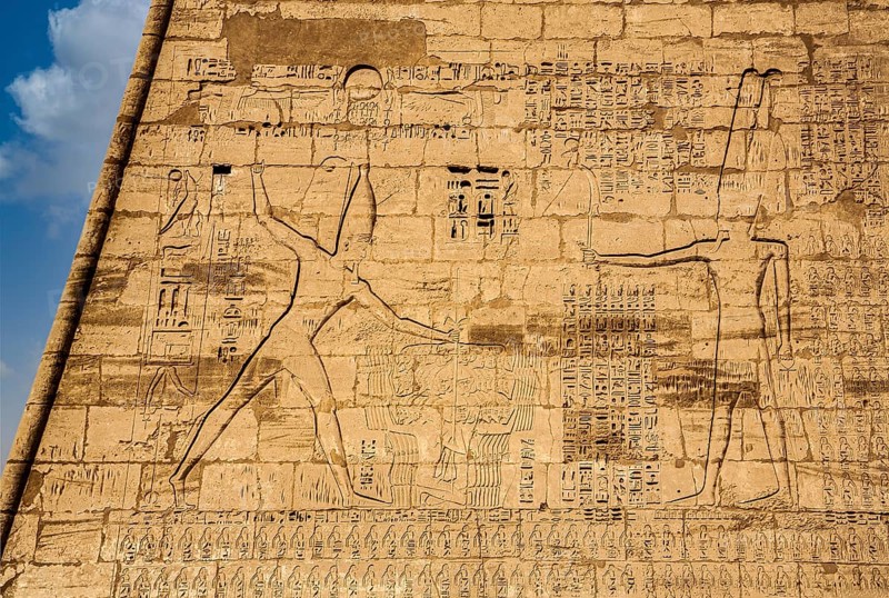 1st pylon in the funerary temple decorated with oversized relief depictions showing the pharaoh in typical displays of power slaying enemies in front of a deity