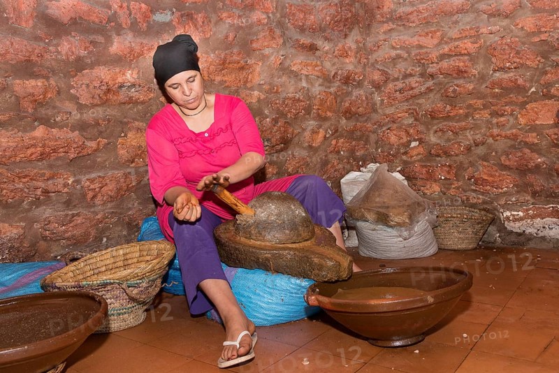Woman grinding the seed flakes of the argan nut in a stone mill