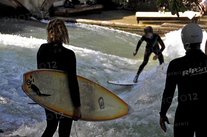 Sufers watch surfers riding the wave at the Eisbach