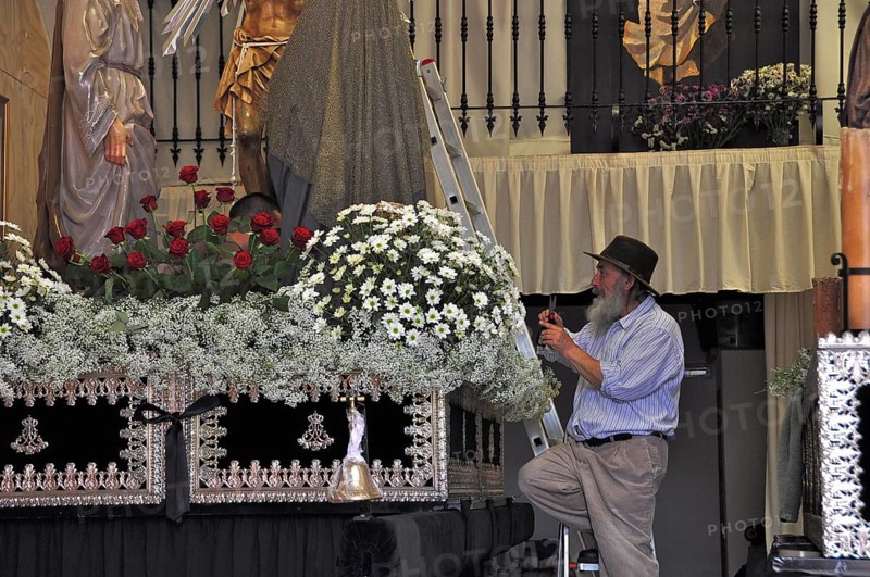 Old man with hat decorates altar in church for Easter procession