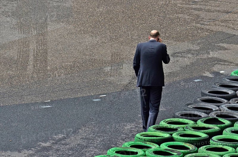 Man with mobile phone to ear in front of stacked car tyres at racecourse