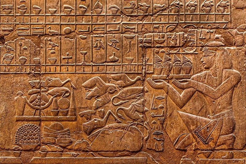 The kneeling king in front of a row of offerings