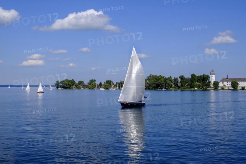 White sailing boat in front of Fraueninsel with Frauenwoerth Monastery
