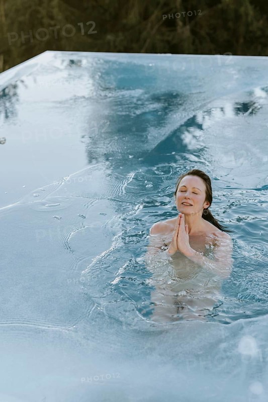 Woman folds her hands while ice bathing in the pool