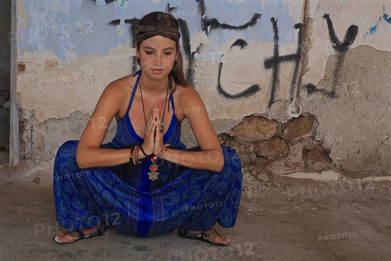 Young woman with headband doing yoga exercise with folded hands in squat position