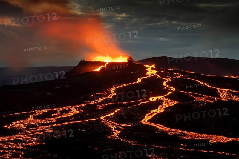 Lava spurting out of crater and reddish illuminated smoke cloud