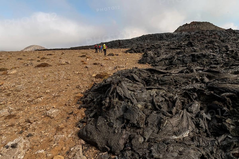 Tourists walk along cooled lava flows