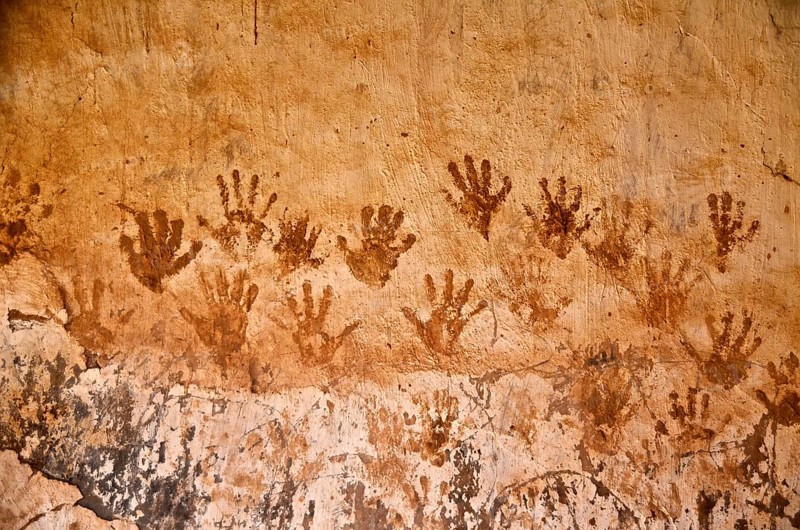 Handprints with henna on clay house wall
