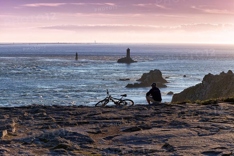 Cyclist sitting on rocky coast