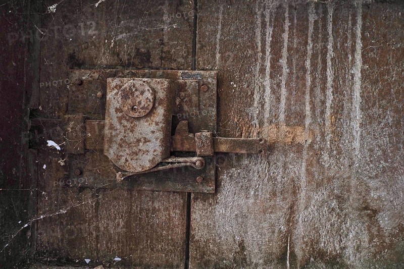 Rusty door lock with cobwebs on wooden door