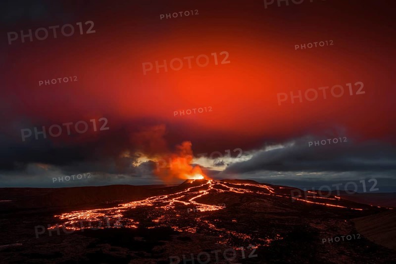 Lava spurting out of crater and reddish reflection on cloud