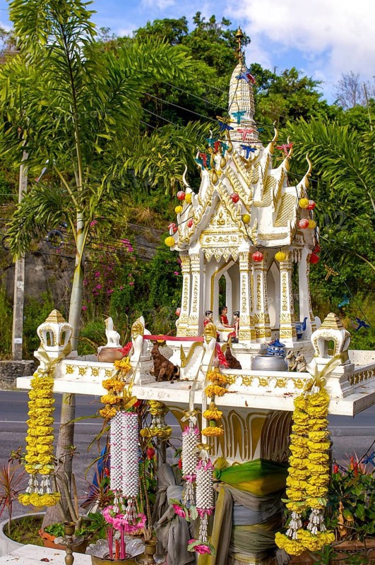 Buddhist spirit house Spirit house with offerings and floral decorations