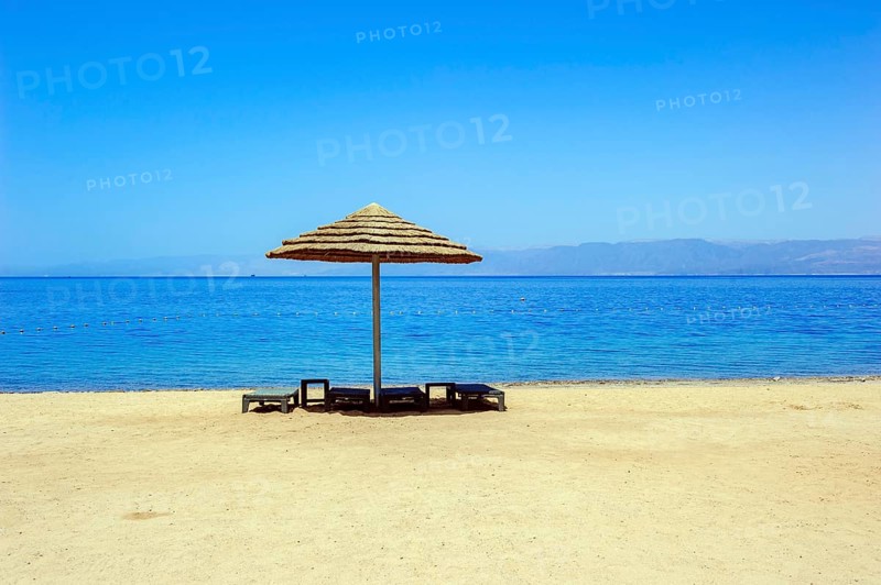 Abandoned empty beach chairs under sunshade on empty beach without tourists in lockdown