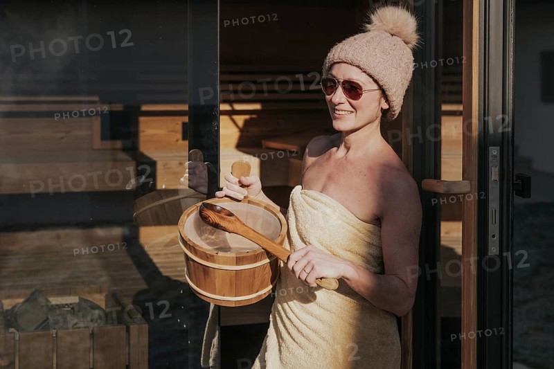 Woman with infusion tub in front of the sauna
