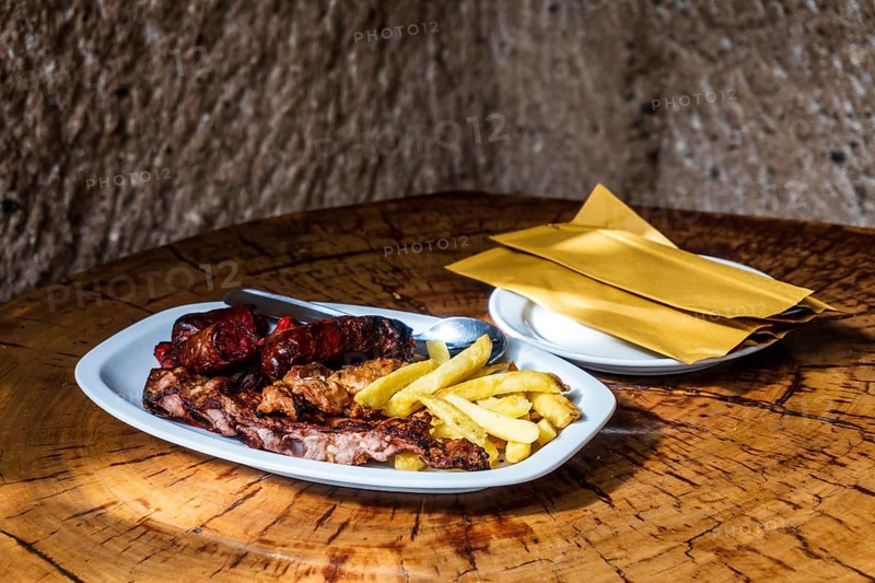 Mixed meat barbecued and served with french fries in restaurant in the cave