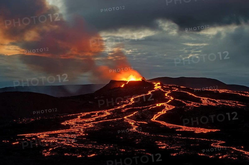 Lava spurting out of crater and reddish illuminated smoke cloud