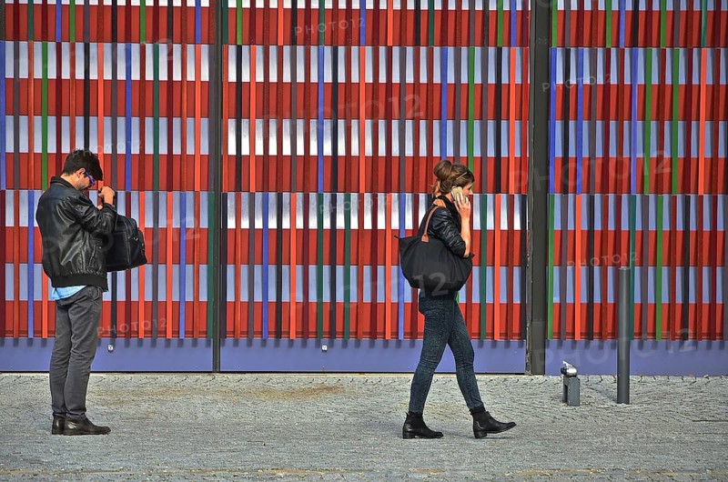 Man looking into bag and young woman talking on phone in front of colourful striped facade of Museum Brandhorst